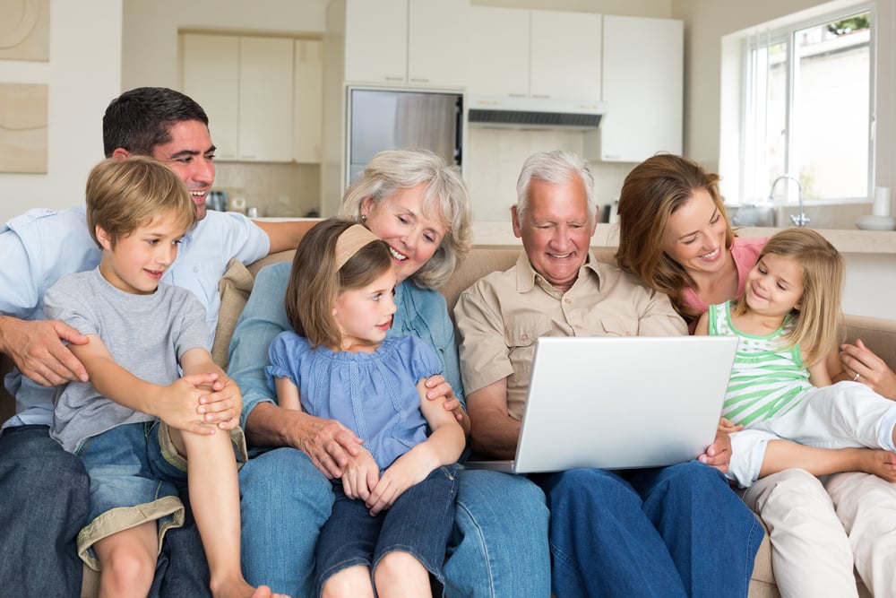 Smiling multigeneration family using laptop in living room Smiling multigeneration family using laptop in living room